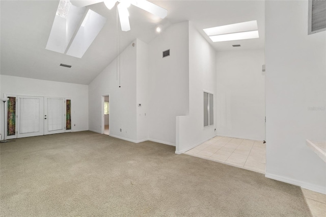 unfurnished living room with ceiling fan, light colored carpet, high vaulted ceiling, and a skylight