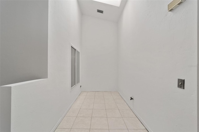 unfurnished room with light tile patterned floors and a skylight