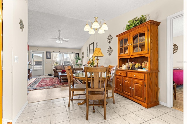 dining space featuring vaulted ceiling, ceiling fan with notable chandelier, a textured ceiling, and light tile patterned floors