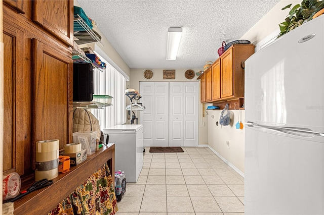 washroom with a textured ceiling and light tile patterned flooring