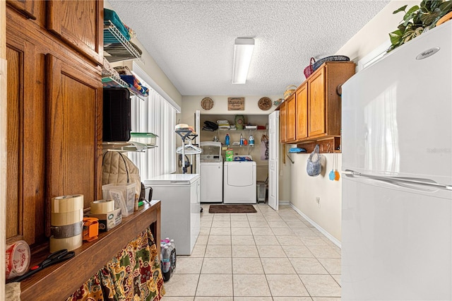 laundry room with washer and clothes dryer, a textured ceiling, and light tile patterned floors