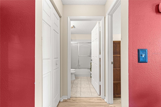 hall featuring light hardwood / wood-style floors and a textured ceiling