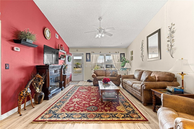 living room featuring lofted ceiling, ceiling fan, hardwood / wood-style flooring, and a textured ceiling