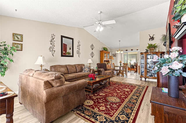 living room with lofted ceiling, ceiling fan with notable chandelier, a textured ceiling, and light wood-type flooring