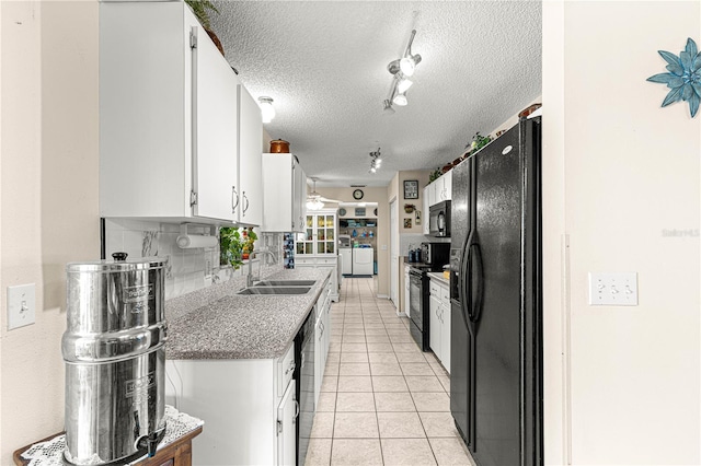 kitchen featuring sink, black appliances, white cabinets, light tile patterned flooring, and decorative backsplash