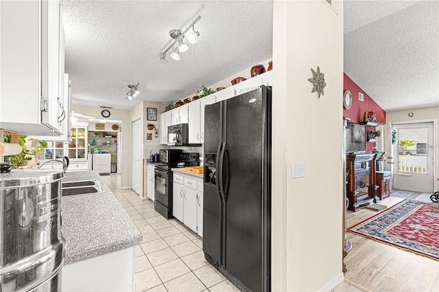 kitchen featuring sink, light tile patterned floors, white cabinetry, black appliances, and a textured ceiling