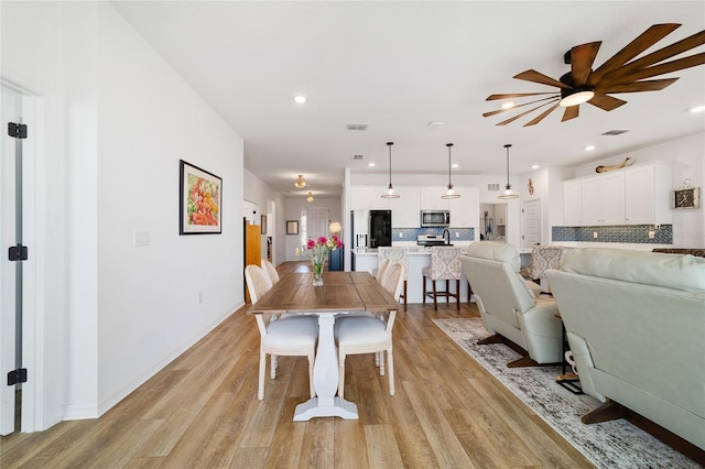 dining space with ceiling fan and light wood-type flooring