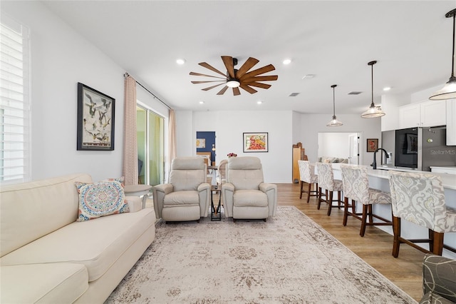 living room with light hardwood / wood-style flooring and ceiling fan