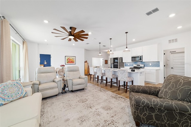 living room featuring sink, hardwood / wood-style flooring, and ceiling fan