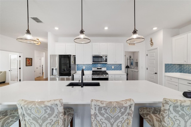 kitchen with sink, hanging light fixtures, a spacious island, and appliances with stainless steel finishes