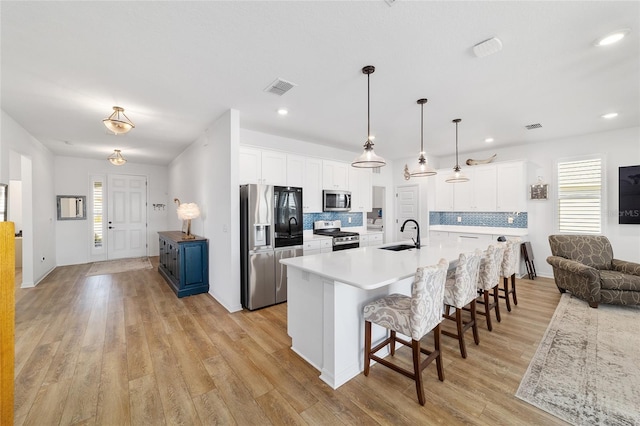 kitchen with appliances with stainless steel finishes, a breakfast bar, blue cabinets, white cabinetry, and a large island