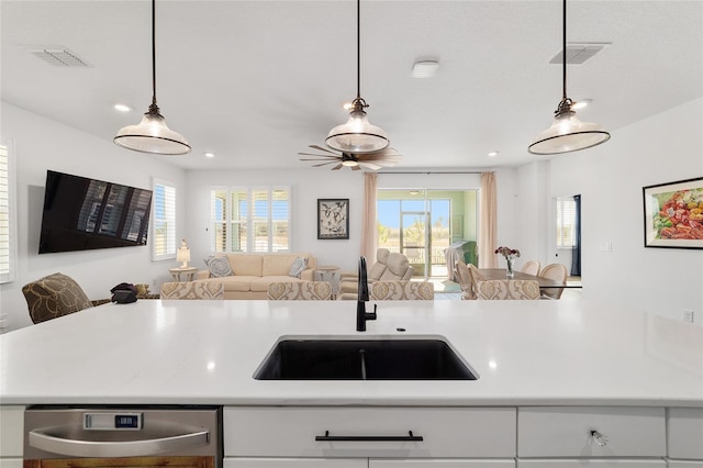 kitchen with white cabinetry, sink, stainless steel dishwasher, and decorative light fixtures