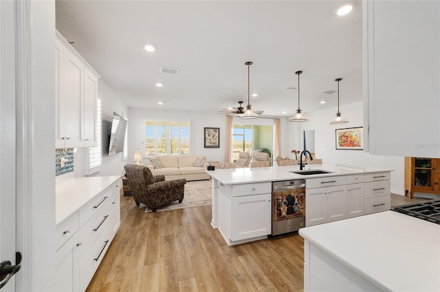 kitchen featuring sink, hanging light fixtures, an island with sink, white cabinets, and light wood-type flooring