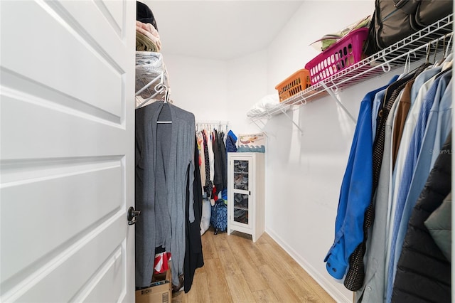 walk in closet with light hardwood / wood-style flooring