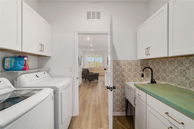 washroom with cabinets, washer and dryer, and light wood-type flooring