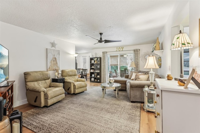 living room with ceiling fan, hardwood / wood-style floors, and a textured ceiling