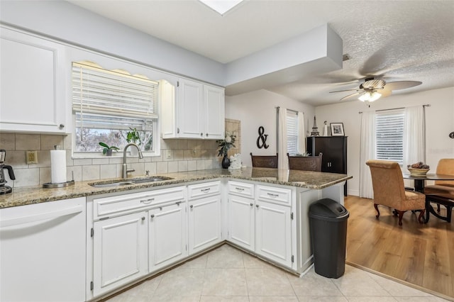 kitchen featuring sink, white cabinets, kitchen peninsula, stone counters, and backsplash