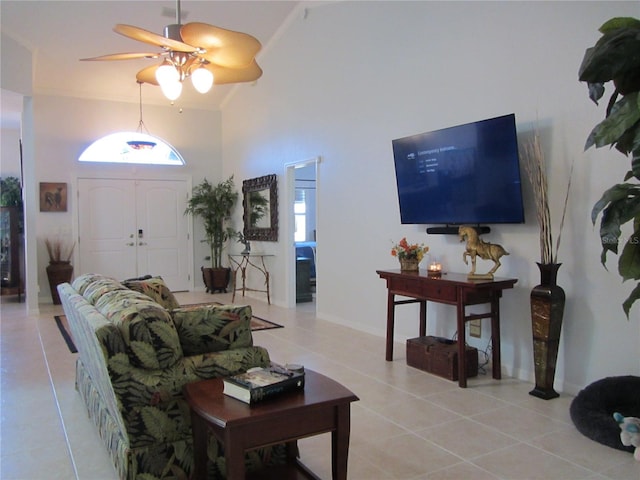 living room with light tile patterned flooring, ceiling fan, ornamental molding, and a high ceiling