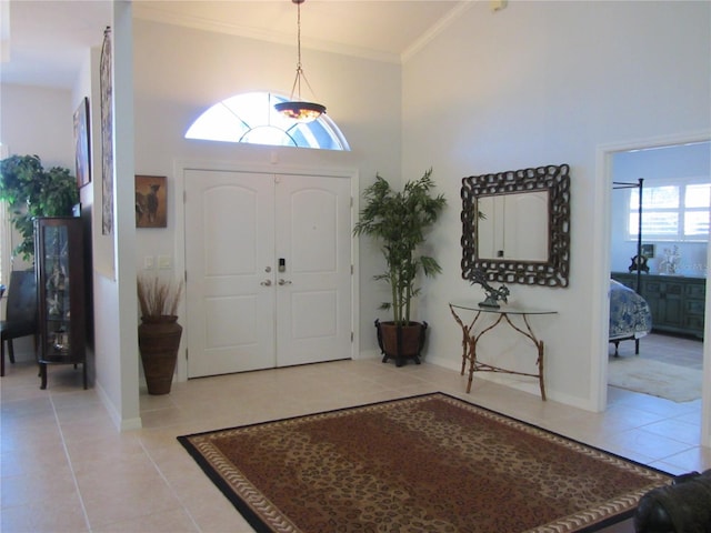 entryway with light tile patterned flooring, a towering ceiling, and crown molding