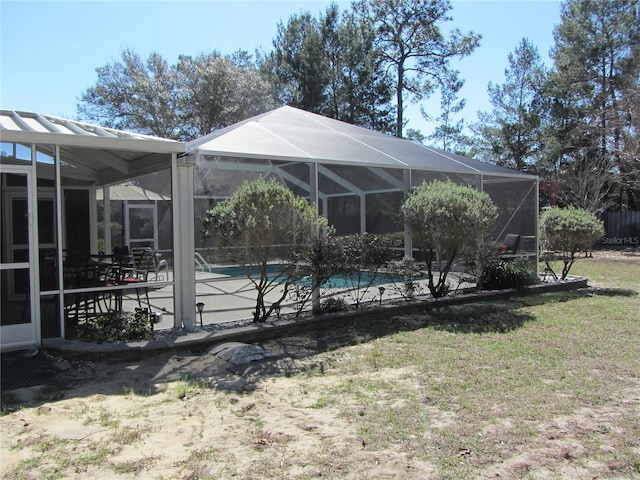 rear view of property with a lanai and a yard