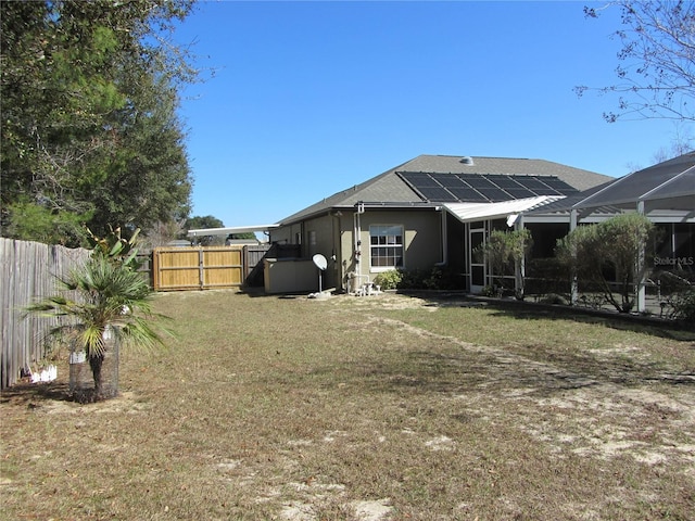 rear view of house featuring a yard and solar panels