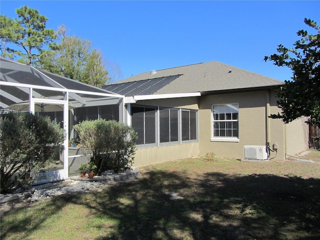 back of property with glass enclosure, ac unit, and a lawn