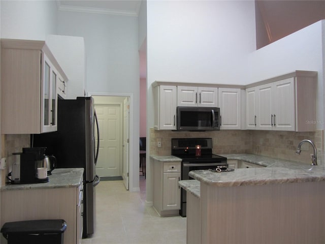 kitchen with ornamental molding, light stone counters, a high ceiling, and kitchen peninsula