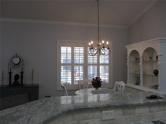 kitchen with an inviting chandelier, decorative light fixtures, light stone counters, and crown molding