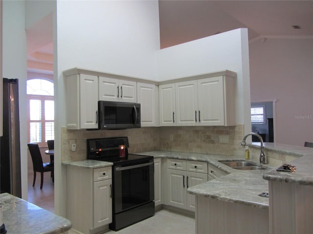 kitchen with sink, white cabinets, kitchen peninsula, light stone countertops, and black / electric stove