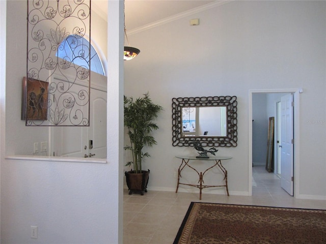 corridor with a high ceiling, ornamental molding, and light tile patterned floors