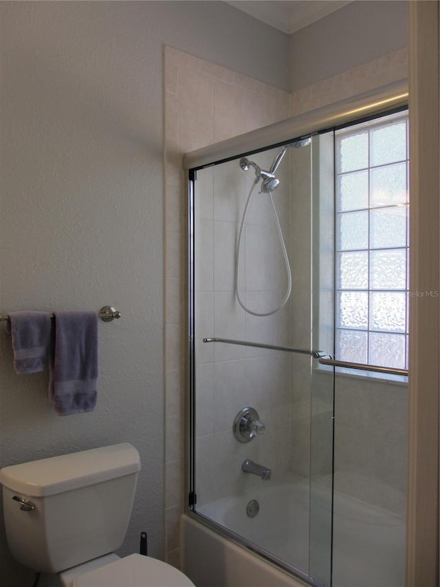 bathroom with toilet and combined bath / shower with glass door