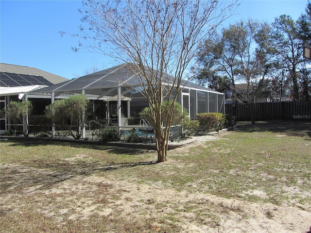 rear view of house with a lawn and glass enclosure