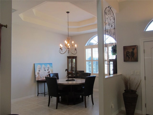 tiled dining space featuring a chandelier and a tray ceiling