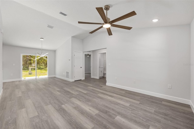 unfurnished living room with ceiling fan with notable chandelier, baseboards, wood finished floors, lofted ceiling, and visible vents