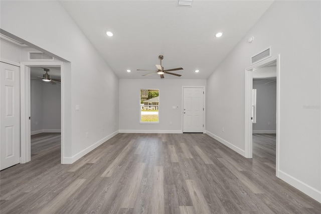 unfurnished living room featuring a ceiling fan, baseboards, visible vents, and wood finished floors