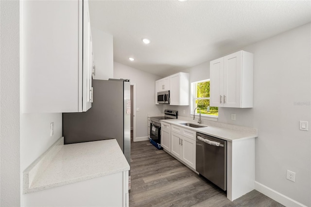 kitchen with white cabinets, baseboards, appliances with stainless steel finishes, and a sink