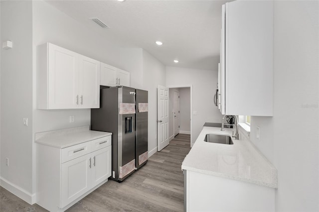 kitchen with a sink, light wood-style flooring, white cabinetry, and stainless steel appliances