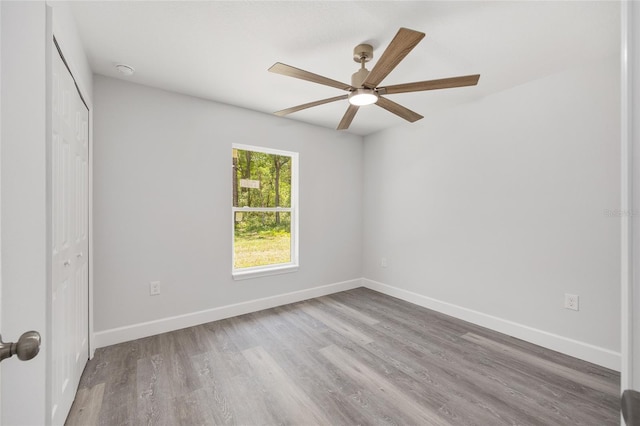 unfurnished bedroom with a closet, baseboards, ceiling fan, and wood finished floors