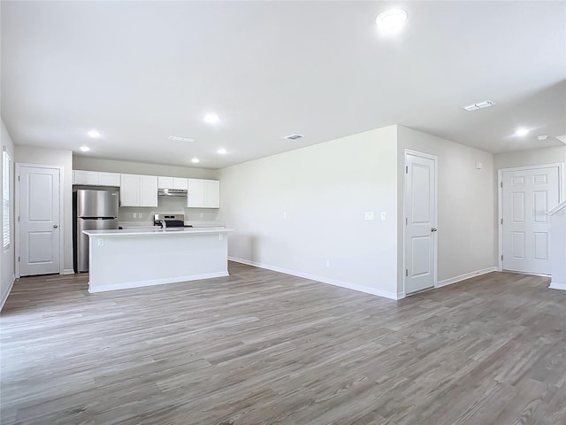 35 Wood Acre Ln, Palm Coast, FL 32164 - kitchen featuring stainless steel appliances, an island with sink, white cabinetry, and light hardwood / wood-style flooring