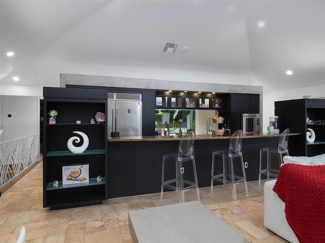 bar featuring lofted ceiling, wall oven, and built in fridge