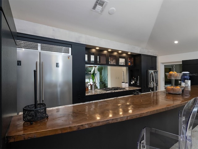 bar with vaulted ceiling and stainless steel appliances