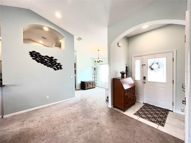 carpeted foyer entrance with an inviting chandelier and lofted ceiling