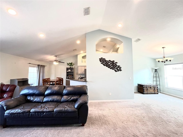 living room with ceiling fan with notable chandelier, vaulted ceiling, and light carpet