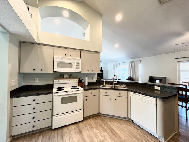 kitchen featuring sink, light wood-type flooring, kitchen peninsula, white appliances, and a healthy amount of sunlight