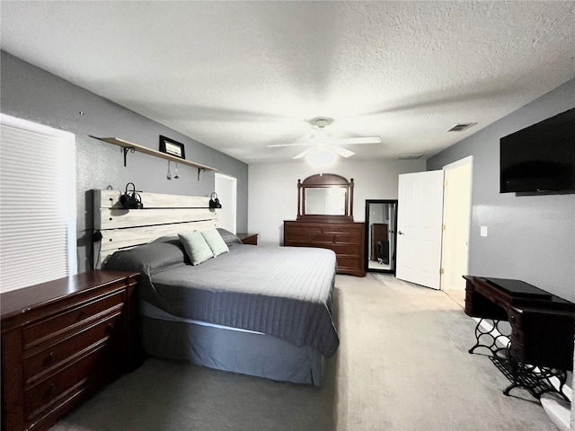 bedroom featuring light colored carpet, a textured ceiling, and ceiling fan