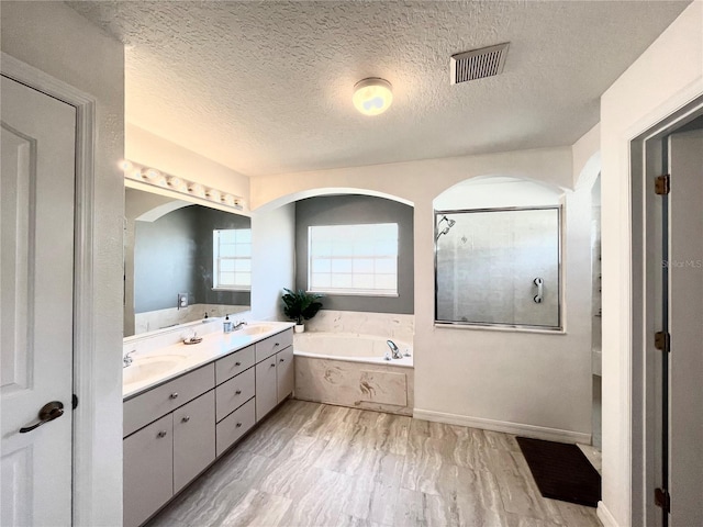 bathroom featuring vanity, shower with separate bathtub, and a textured ceiling