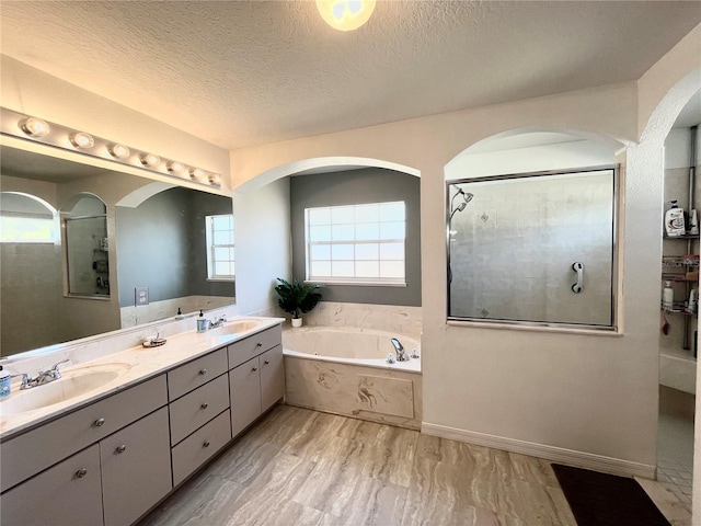 bathroom featuring independent shower and bath, vanity, and a textured ceiling