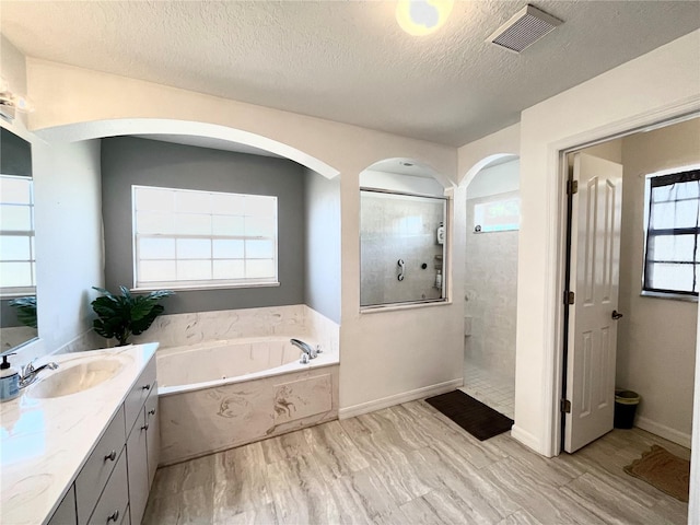 bathroom featuring vanity, hardwood / wood-style flooring, plus walk in shower, and a textured ceiling