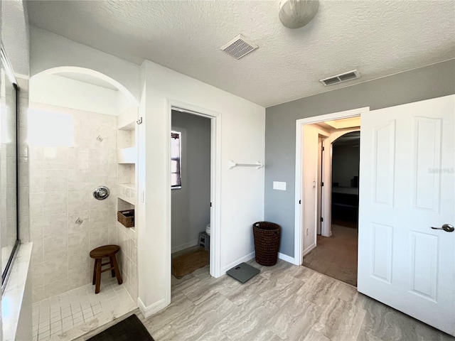 bathroom featuring a tile shower and a textured ceiling