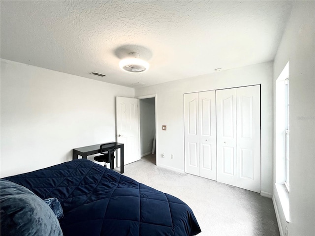 carpeted bedroom featuring a textured ceiling and a closet